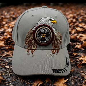 May include: Gray baseball cap featuring an embroidered eagle design with a Native American theme. The eagle has a white head, yellow beak, and brown and white feathers. The text "NATIVE PRIDE" is embroidered on the side.
