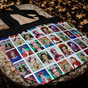 May include: Black tote bag featuring a colorful pattern of Frida Kahlo portraits. The bag has a black handle and is made of a durable fabric. The portraits are in a grid pattern with various colors and styles.