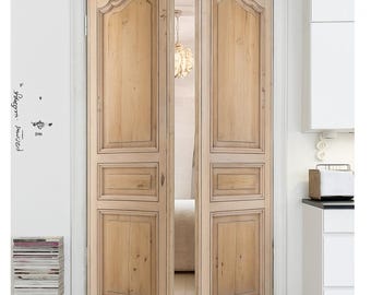 May include: A pair of light-toned wooden double doors featuring a classic arched top panel design and rectangular lower panels. The doors are set within a white door frame, showcasing a natural wood grain finish with visible knots and texture.