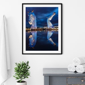 Large blue horse head sculptures in Scotland with water reflection at night.