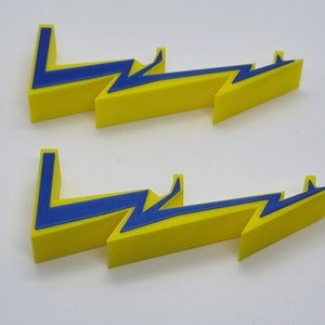 May include: Two sets of three yellow lightning bolt shapes with blue outlines. The shapes are layered on top of each other.