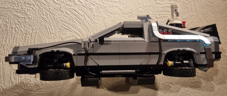 May include: A gray Lego model of the DeLorean time machine from the Back to the Future movie series. The model has a detailed interior and exterior, including the iconic flux capacitor and gull-wing doors.