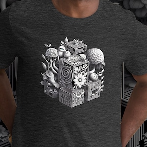 Puede incluir: Una camiseta gris oscuro jaspeada con un gráfico blanco de un cubo 3D formado por cubos más pequeños. El gráfico incluye una variedad de elementos inspirados en la naturaleza, como flores, hongos y pájaros.