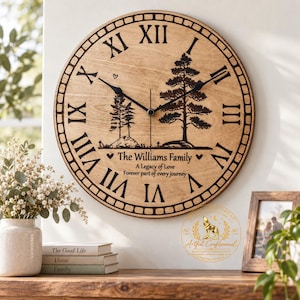 May include: A round wooden wall clock with black Roman numerals and a central graphic of two pine trees. The text reads The Williams Family, A Legacy of Love, Forever part of every journey. It features black clock hands and a border design.