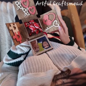 May include: A wooden box with a heart-shaped lock and key, a jigsaw piece, and a photo of a couple. The box is open and contains a red sweet. The text "Boyfriend" is written on the box.