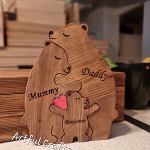 May include: Wooden cutout of a family of bears, with the words "Daddy", "Mummy", and "Benjamin" inscribed. The bear representing the child is holding a pink heart.