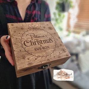 May include: A wooden box with a hinged lid and a metal clasp. The box is decorated with a snowflake design and the text "Patricia's Christmas Eve Box".
