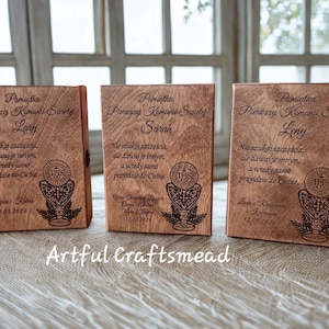 May include: Three wooden keepsake boxes with engraved text and religious imagery. Each box is a light brown colour and features a chalice design with the text "Pamiatka Pierwszej Komunii Swietej" and a name. The boxes are closed.