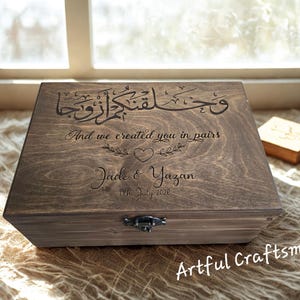 May include: A stained wooden box with engraved Arabic calligraphy and the English text "And we created you in pairs." The box is inscribed with "Jade & Yazan 11th July 2020" and has a metal clasp.