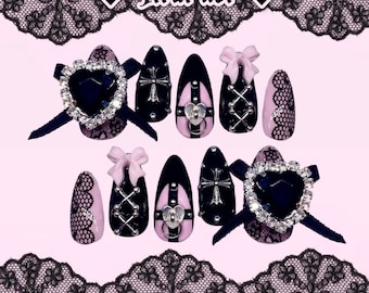 May include: A set of pink and black press-on nails with a gothic and punk theme. The nails feature black lace, hearts, crosses, and studs. The text "Jiirai kei" is written in black on a white background.