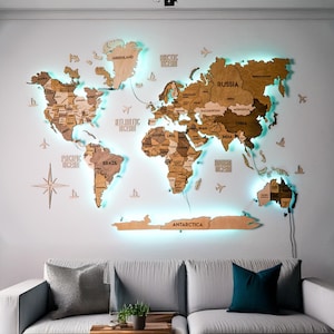 May include: A large, multi-layered wooden world map wall art piece featuring varying shades of brown wood, engraved country names, and a glowing cyan LED backlight. The map includes decorative wooden icons of airplanes, ships, and a compass rose.