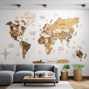 May include: A large wooden world map wall art installation featuring various shades of brown and tan wood. The map includes labeled continents, countries, and oceans, along with decorative wooden airplane and sailboat icons and a compass rose.