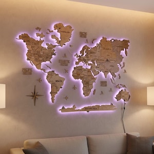 May include: A wooden world map with purple LED backlighting mounted on a wall. The map includes country outlines and ocean names. A compass and airplane cutouts are also on the wall. The map is above a gray sofa.