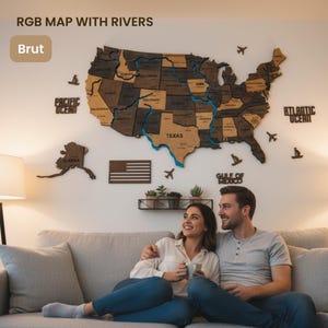 Pode incluir: Um mapa de madeira dos Estados Unidos com detalhes de rios azuis e nomes de estados. O mapa está montado em uma parede branca, com recortes decorativos de aviões e barcos. O texto "RGB MAP WITH RIVERS" está no topo.