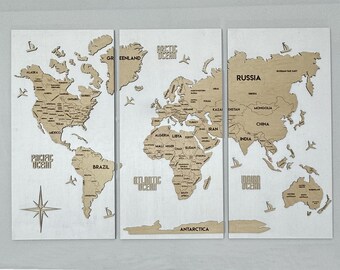 Puede incluir: Un mapa del mundo de madera en tres paneles con continentes y océanos recortados. El mapa está etiquetado con los nombres de los países y continentes, incluyendo "Océano Ártico", "Océano Pacífico", "Océano Atlántico", "Océano Índico", "Rusia", "Groenlandia", "Brasil", "China", "India", "Antártida" y "Alaska".