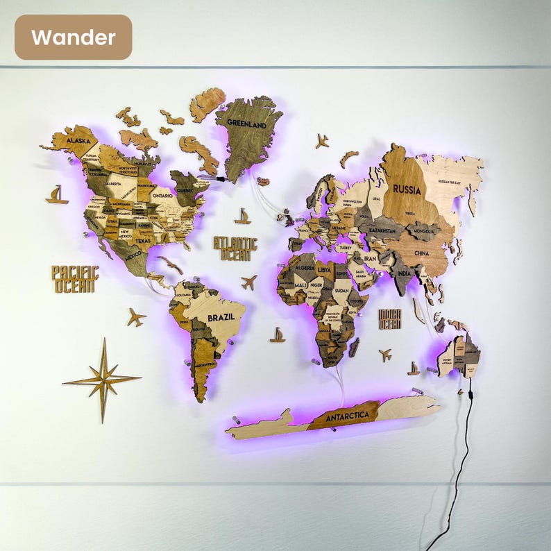 Op de afbeelding: Een meerlaagse houten wereldkaart als wanddecoratie met gegraveerde landnamen, staten en oceanen. De kaart bevat decoratieve houten vliegtuigen, schepen en een windroos, verlicht door paarse led-achtergrondverlichting met een stroomkabel.