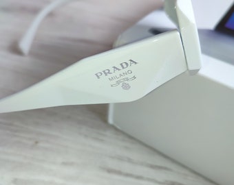 witte Prada-zonnebril van acetaat met het logo aan de zijkant en gegraveerd op de linkerlens. Prada-bril. Prada-zonnebril