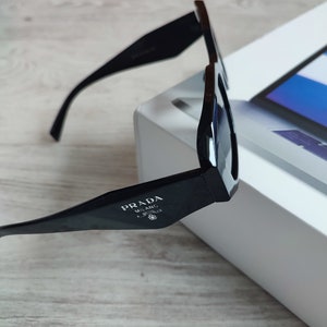 Weiße Prada-Sonnenbrille aus Acetat mit Logo an der Seite und eingravierter Prada-Brille auf der linken Linse. Prada-Sonnenbrille noir