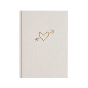 May include: A white linen-textured journal with a gold heart and arrow design.