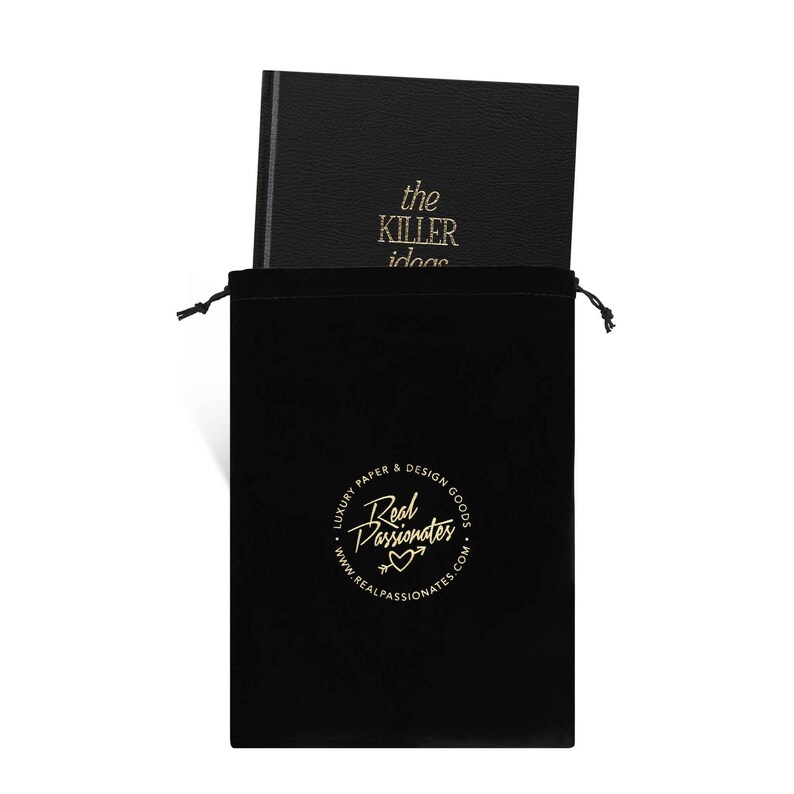 May include: A black velvet pouch with a gold drawstring closure. The pouch has a gold circle logo that reads "Luxury Paper & Design Goods Real Passionates www.realpassionates.com". The pouch contains a black leather-bound journal with gold lettering that reads "the killer ideas".