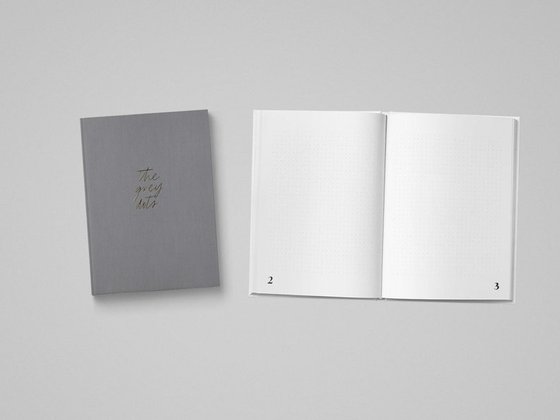 May include: A gray notebook with the text "the grey hats" on the cover. The notebook is open to a blank page with a grid pattern.