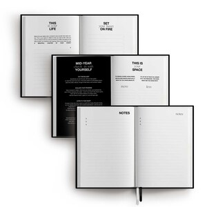 May include: Three open black hardcover journals with white pages are stacked on a white background. The top journal reads "THIS IS YOUR LIFE" and "SET YOUR HEART ON FIRE". The middle journal reads "MID-YEAR check-in with YOURSELF". The bottom journal reads "NOTES".
