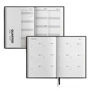 May include: Two open black-bound planners with white pages. The top planner displays a yearly calendar layout, while the bottom planner shows a monthly format. The text "Quarter One" is printed on the side of the top planner.