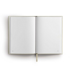 May include: A beige notebook with a dotted page layout and a gold ribbon bookmark. The notebook is open to a blank page.