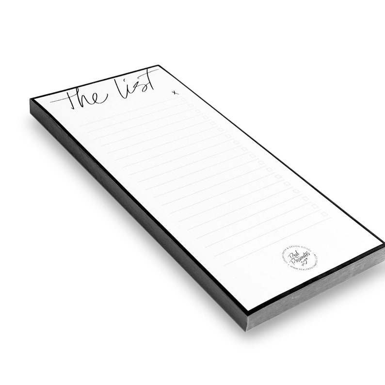 May include: A white notepad with a black border and the words "the list" written in black cursive. The notepad has a lined interior and a small circle logo at the bottom with the text "Pink Presents".