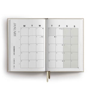 May include: An open planner showing a January calendar spread with a beige cover and two ribbon bookmarks. The grid layout displays days of the week, dates, and moon phase icons. Text includes JANUARY, CALENDAR WEEK, and CW 53-04 in black font.