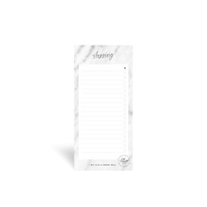 May include: White marble notepad with a black checklist and the text "Shopping" at the top. The notepad has a black circle at the bottom with the text "But less & choose well" and a smaller circle with the text "Real Moments" inside.
