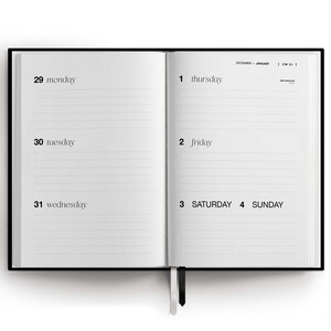 May include: Open black hardcover planner with lined pages. The left page shows Monday, Tuesday, and Wednesday dates. The right page shows Thursday, Friday, Saturday, and Sunday dates. A black ribbon bookmark is visible.