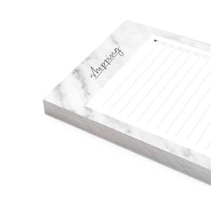 May include: A white notepad with a marble pattern and the word "Shopping" written in black cursive. The notepad has a checklist with checkboxes and lined paper for writing.
