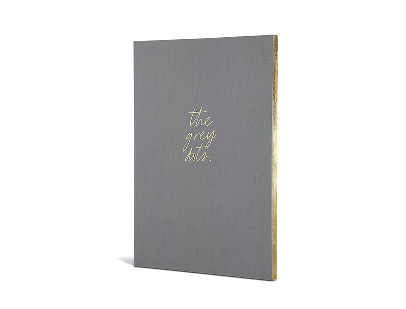 May include: A gray linen notebook with gold foil lettering that reads "the grey dots."
