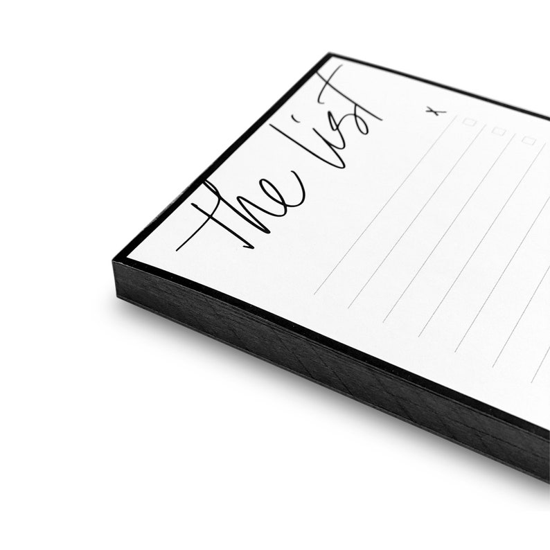 May include: A white notepad with a black border and the text "The List" written in black cursive. The notepad has lined paper and a check box at the top right corner.