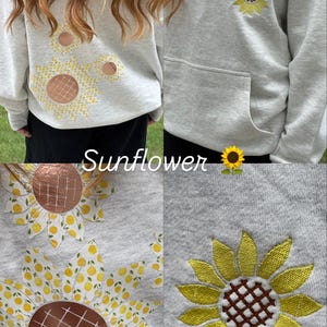 Puede incluir: Sudadera con capucha gris claro con un dise&ntilde;o de girasol. El girasol tiene p&eacute;talos amarillos y un centro marr&oacute;n. La palabra "Sunflower" est&aacute; impresa en blanco. La sudadera tiene un bolsillo delantero y una capucha con cord&oacute;n.