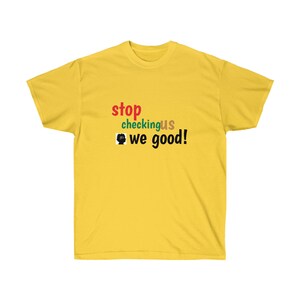 Puede incluir: Camiseta amarilla con el texto "stop checking us we good!" en rojo, verde, marrón y negro.