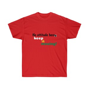 Puede incluir: Una camiseta roja de manga corta con el texto negro 'No attitude here' seguido de un pequeño icono negro, con las palabras 'keep' en blanco, 'it' en amarillo y 'moving!' en verde impresas debajo de la primera línea de texto en el pecho.