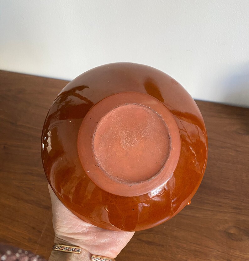May include: A brown ceramic vase with a glazed finish. The vase has a rounded shape and a wide opening.