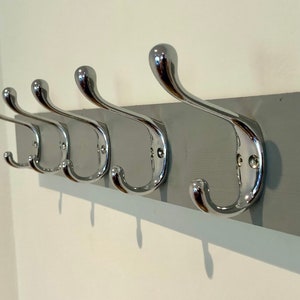 K&ouml;nnte beinhalten: Ein grauer, an der Wand montierter Kleiderst&auml;nder mit f&uuml;nf verchromten Haken.