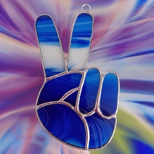 Gesto della mano con segno di pace in vetro colorato blu