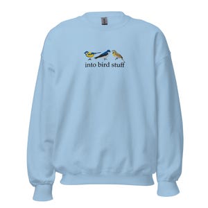 Puede incluir: Sudadera azul claro con un gráfico de tres pájaros y el texto "into bird stuff".