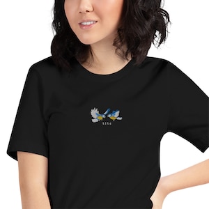May include: Black t-shirt with an embroidered design of two blue birds facing each other. The text "tits" is embroidered below the birds.