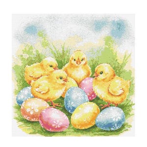 Puede incluir: Cinco pollitos amarillos rodeados de huevos de Pascua coloridos. Los pollitos están acurrucados en una cama de hierba verde con un cielo azul en el fondo.