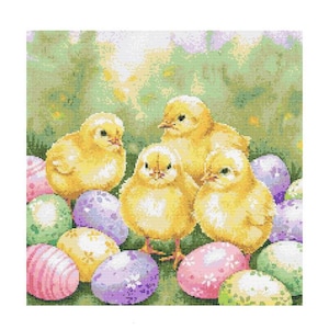 Puede incluir: Cuatro pollitos amarillos rodeados de huevos de Pascua coloridos. Los pollitos están sentados en un lecho de hierba verde con un fondo borroso de hojas verdes.