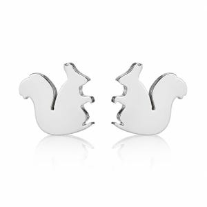 May include: A pair of silver-toned stud earrings shaped like squirrels. Each earring features a smooth, reflective surface and a silhouette of a squirrel sitting upright with its bushy tail curved behind its back, facing toward the center.