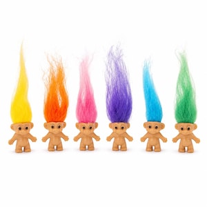 May include: A set of six small plastic troll figurines standing in a row. Each figure has a tan skin tone and a tall, upright tuft of synthetic hair in a different vibrant color: yellow, orange, pink, purple, blue, and green.