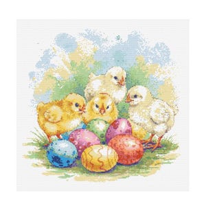 Puede incluir: Cuatro pollitos amarillos y esponjosos se agrupan alrededor de un grupo de huevos de Pascua coloridos. Los pollitos tienen picos amarillos brillantes y los huevos están decorados con diferentes patrones.