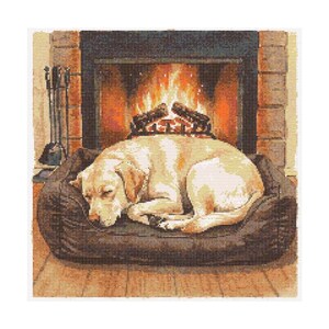 Op de afbeelding: Kruissteekafbeelding van een gele Labrador Retriever hond die vredig slaapt op een bruin hondenbed voor een open haard met een brandend vuur. De open haard is van baksteen, wat een warme en gezellige sfeer creëert.