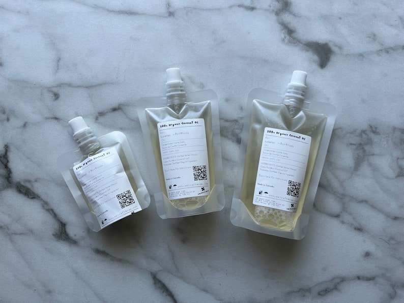 May include: Three clear plastic pouches filled with a light yellow liquid. Each pouch has a white cap and a label that reads "100% Organic Coconut Oil".